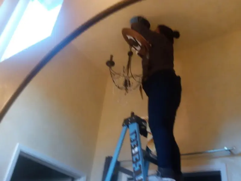 Electrician installing a chandelier in a Ripley residence